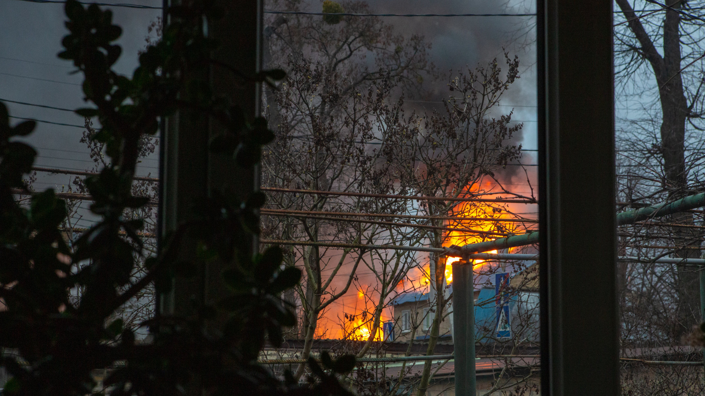 "Zurück in die Ukraine - Die Heimkehr des Fotografen Juri Kosin": Ein Blick aus dem Fenster seines Hauses, ein Haus in der Nachbarschaft wurde bombardiert und steht in Flammen.