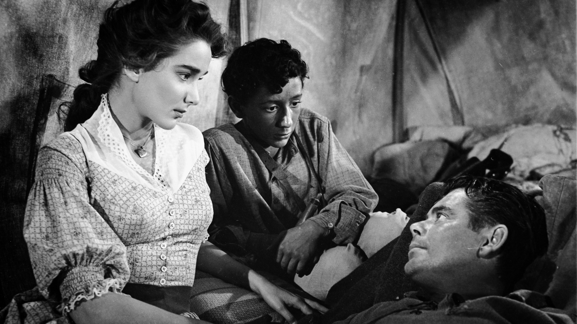 "Der Mann aus Alamo": Beth (Julie Adams) und der junge Carlos (Marc Mark) wachen bei dem verwundeten Stroud (Glenn Ford). Stroud liegt im Zelt und schaut dankbar Beth an, die ihm mitfühlend in die Augen sieht. Auch Carlos betrachtet besorgt den Verletzten.