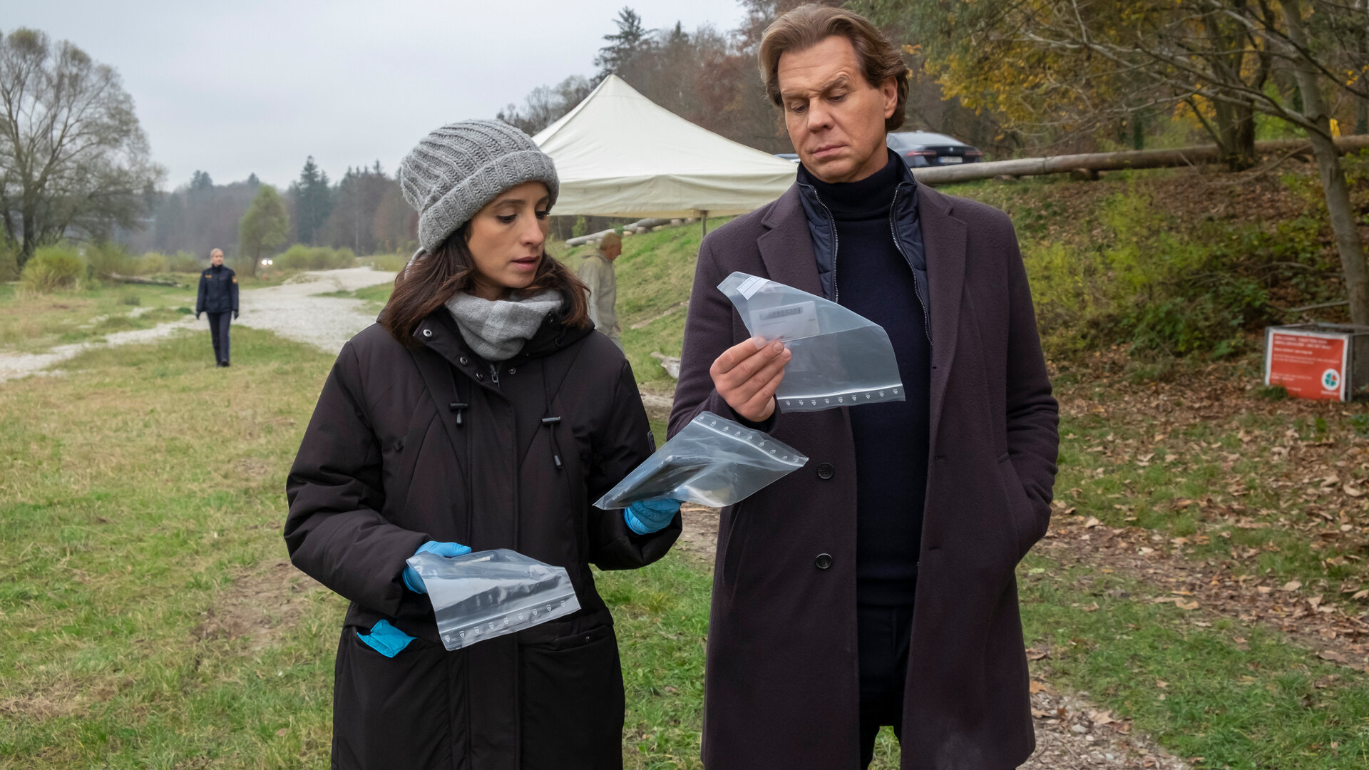 "Der Alte - Abgepfiffen": Annabell Lorenz (Stephanie Stumph) und Caspar Bergmann (Thomas Heinze) stehen auf einem Feldweg und betrachten die eingetüteten Beweismittel, die die beiden in der Hand halten.