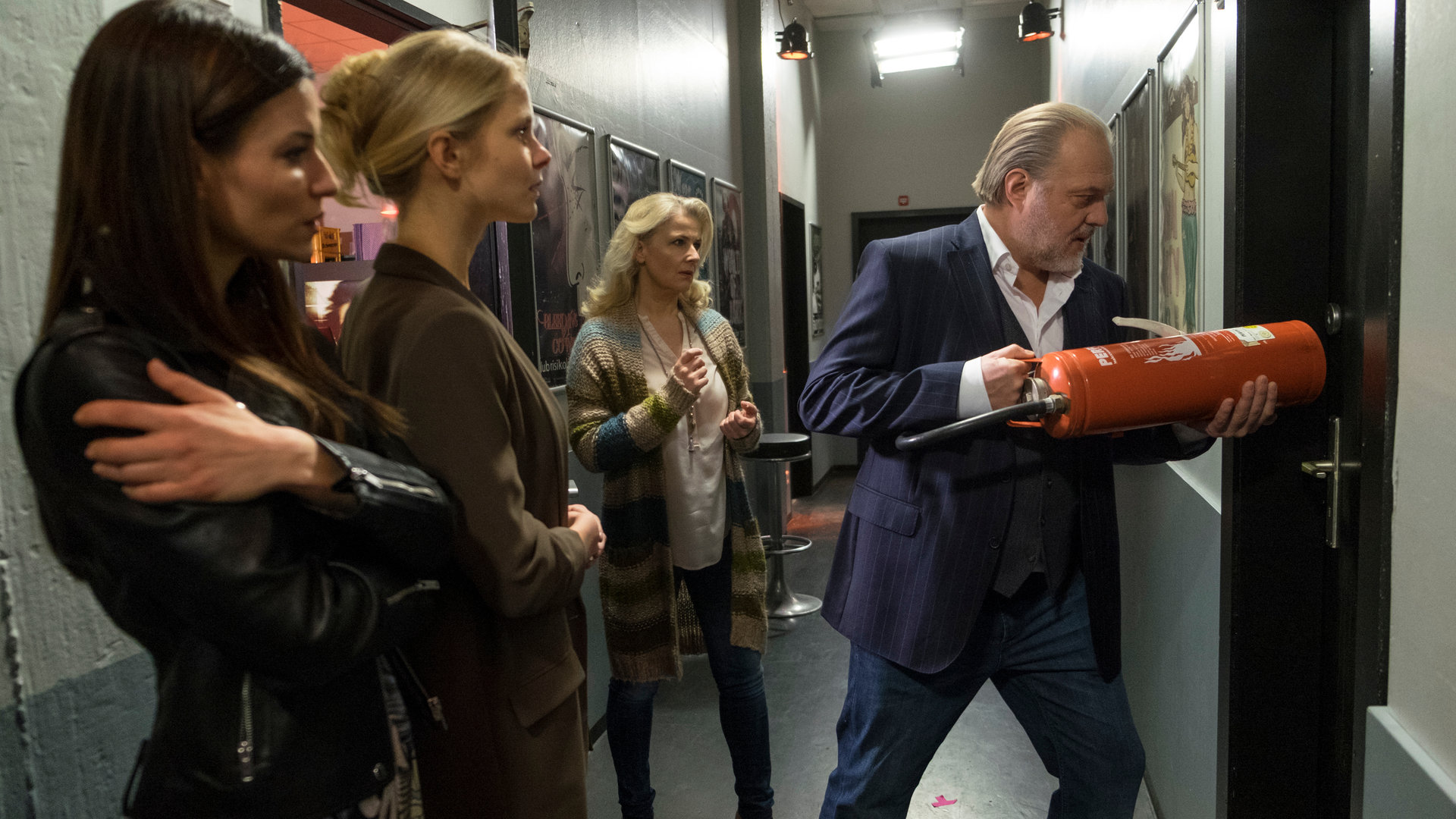 "Der Alte - Die Kunst des Scheiterns": Die Besitzerin des Clubs Anika (Anna Lena Class), Julia Graupner (Sinja Dieks) und Dr. Franziska Sommerfeld (Christina Rainer) sehen aufgeregt dabei zu wie Hauptkommissar Richard Voss (Jan-Gregor Kremp) die verschlossene Toilettentür mit Hilfe eines Feuerlöschers aufbricht.