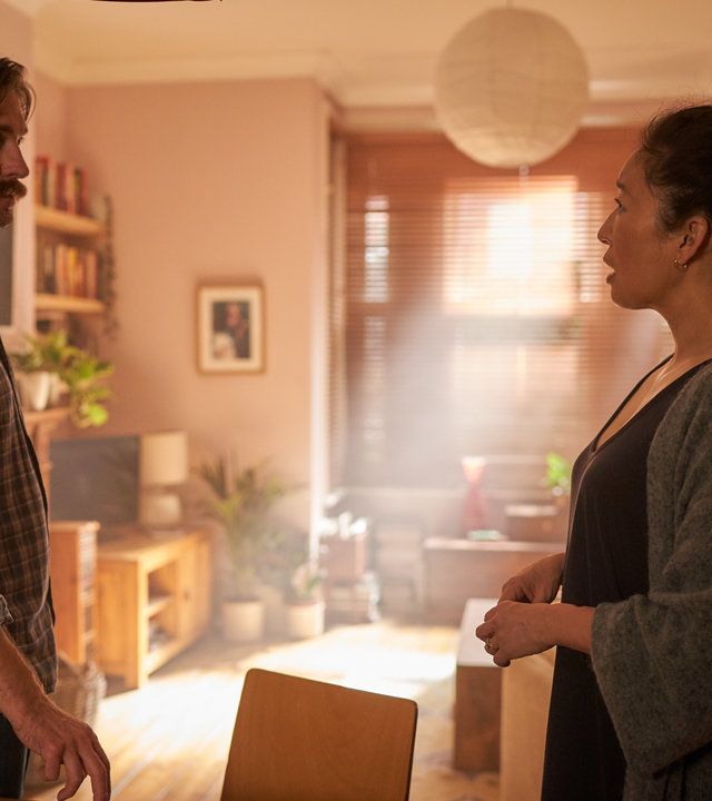 "Killing Eve – Ich soll also niemanden töten?": Niko (Owen McDonnell) steht Eve (Sandra Oh) in einem hell erleuchteten Wohnzimmer gegenüber und starrt sie wütend an.