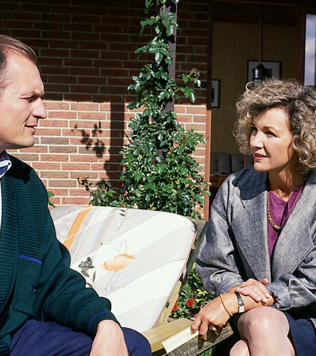 "Der Landarzt - Ein Fremder im Haus": Annemarie Mattiesen (Gila von Weitershausen) sitzt neben Dr. Schneider (Dietrich Mattausch) in einem Garten und schaut ihn besorgt an.