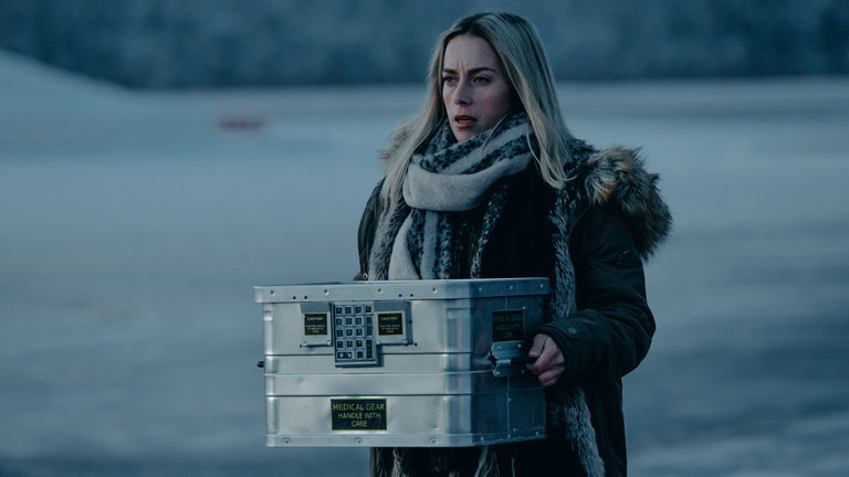 "Arctic Circle - Der unsichtbare Tod (9)": Nina Kautsalo (Iina Kuustonen) steht mit einem Metallkoffer in den Händen vor einer schneebedeckten Landschaft.