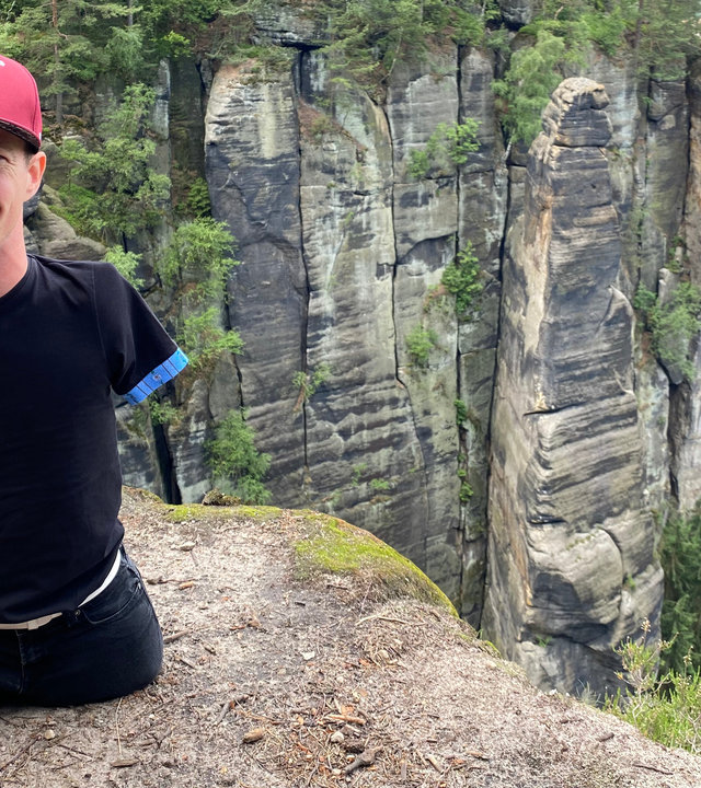 "einfach Mensch: High Hopes - auf zum Gipfel": Janis McDavid befindet sich auf einem Felsen und lacht in die Kamera.