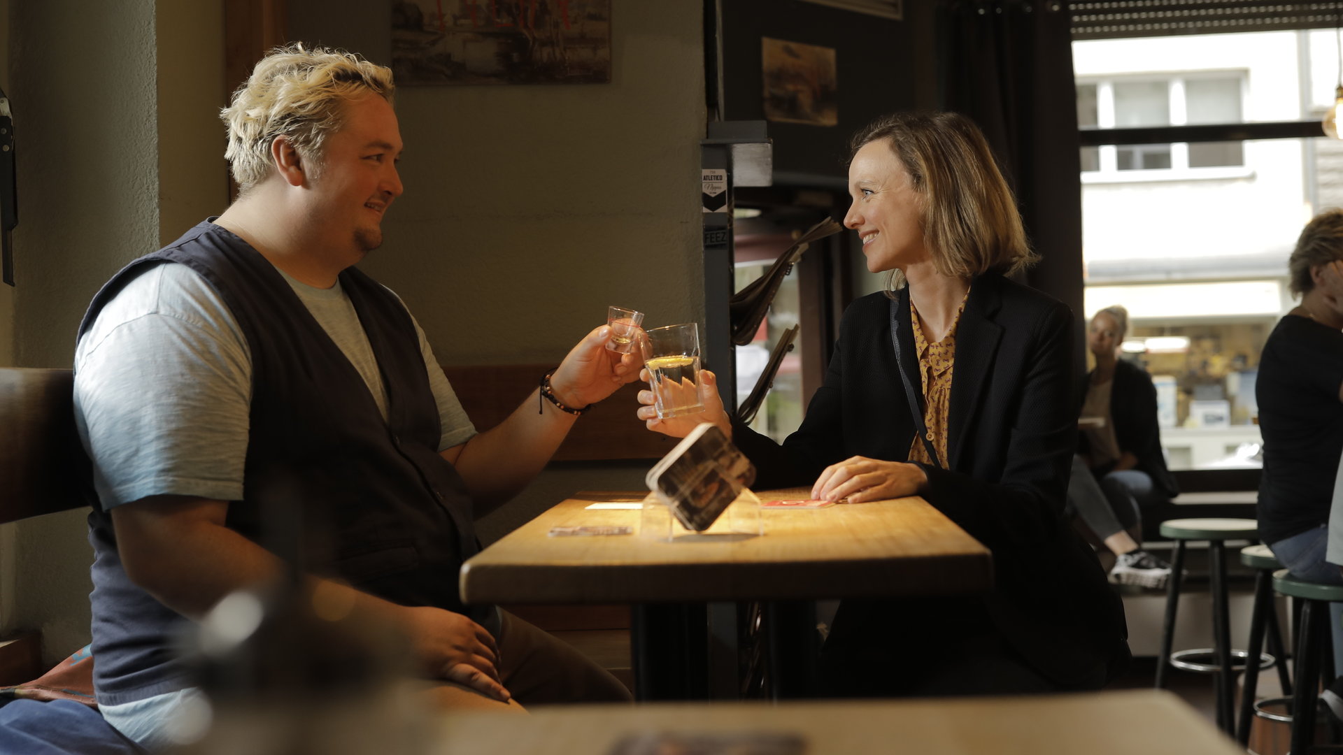 “Andere Eltern - Episode 4“: Malte (Daniel Zillmann) und Anita (Nadja Becker) sitzen in der Kneipe und stoßen mit ihren Getränken an.