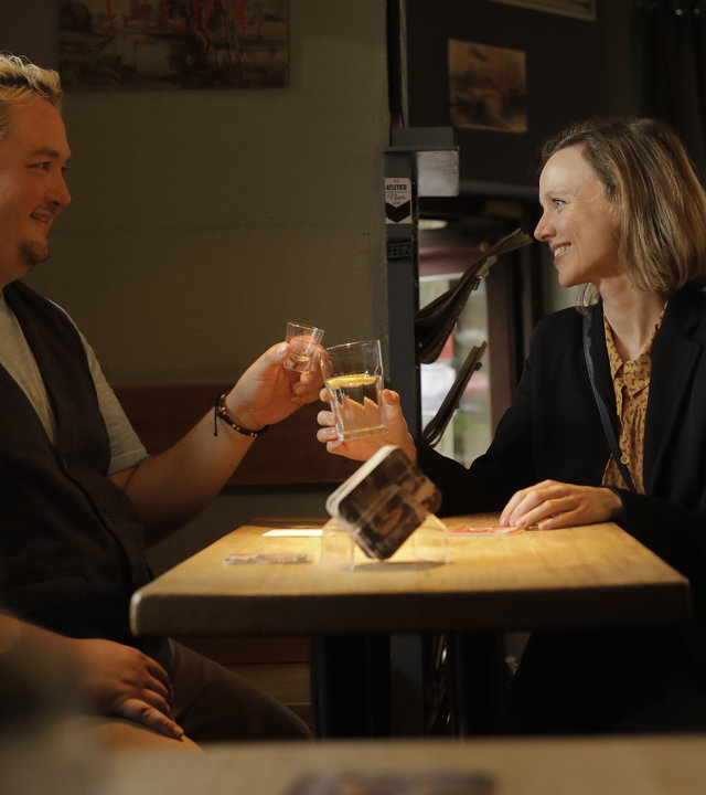“Andere Eltern - Episode 4“: Malte (Daniel Zillmann) und Anita (Nadja Becker) sitzen in der Kneipe und stoßen mit ihren Getränken an.