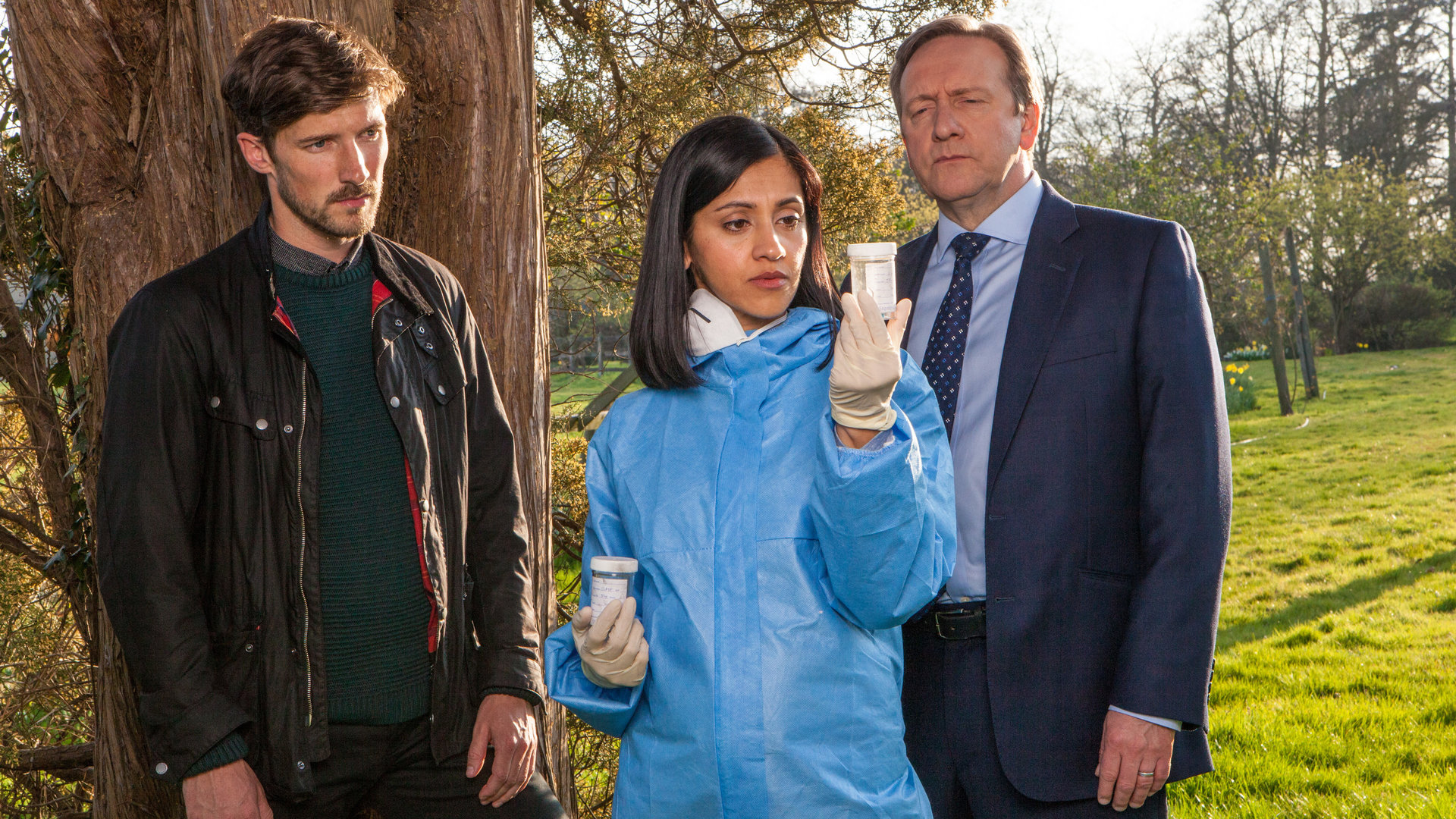 "Inspector Barnaby - Und wo sind die Leichen": Charlie Nelson (Gwilym Lee), Dr. Kam Karimore (Manjinder Virk) und Inspector Barnaby (Neil Dudgeon) haben Indizien gefunden und betrachten ein Reagenzglas mit Textil-Gewebeproben.
