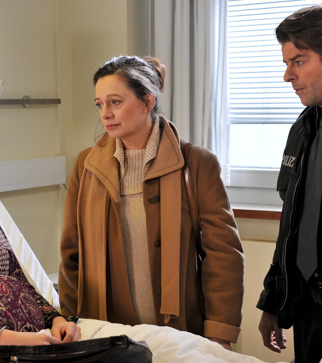 "Notruf Hafenkante - Amerikanische Hochzeit": Linda (Anna Fischer) sitzt in einem Krankenhausbett. Daneben stehen Henning (Uwe Fellensiek) und ihre Mutter Renate (Gudrun Gabriel), die Linda besorgt ansieht.