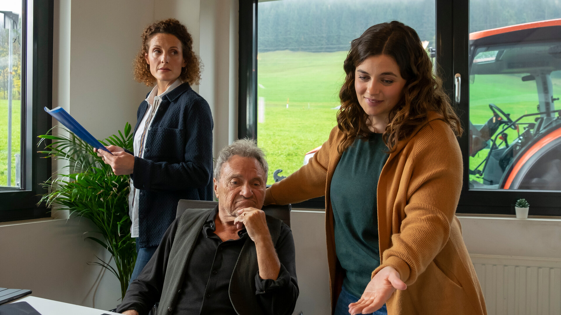 "Der Bergdoktor: Über den Schatten (1)": Im Büro des Landhandels: Rolf Pflüger (Wolfram Berger) sitzt am Schreibtisch und blickt nachdenklich auf den Monitor eines Notebooks. Lilli Gruber (Ronja Forcher) steht neben ihm und zeigt lächelnd mit der Hand darauf. Im Hintergrund steht Caro Pflüger (Barbara Lanz) und beobachtet die beiden.