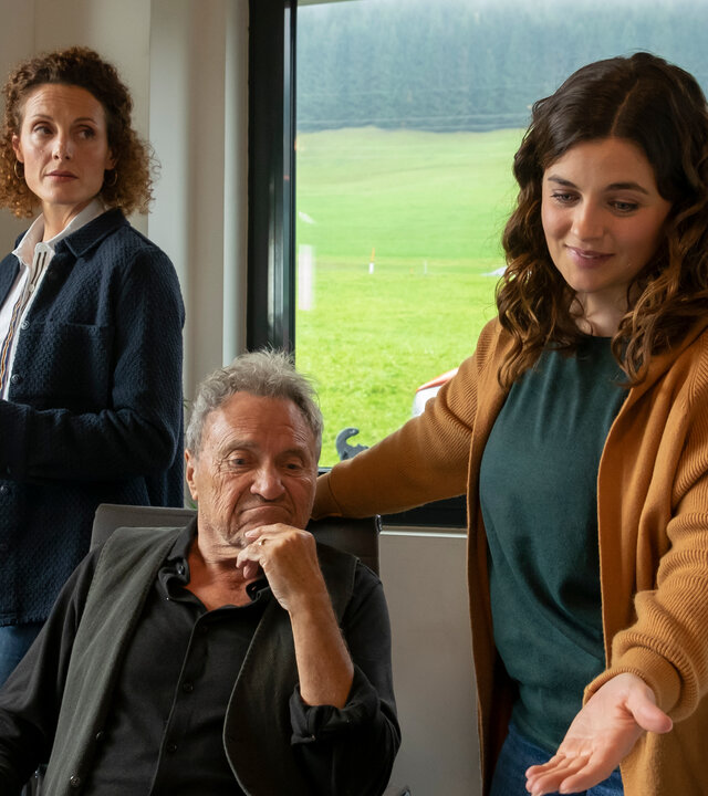 "Der Bergdoktor: Über den Schatten (1)": Im Büro des Landhandels: Rolf Pflüger (Wolfram Berger) sitzt am Schreibtisch und blickt nachdenklich auf den Monitor eines Notebooks. Lilli Gruber (Ronja Forcher) steht neben ihm und zeigt lächelnd mit der Hand darauf. Im Hintergrund steht Caro Pflüger (Barbara Lanz) und beobachtet die beiden.