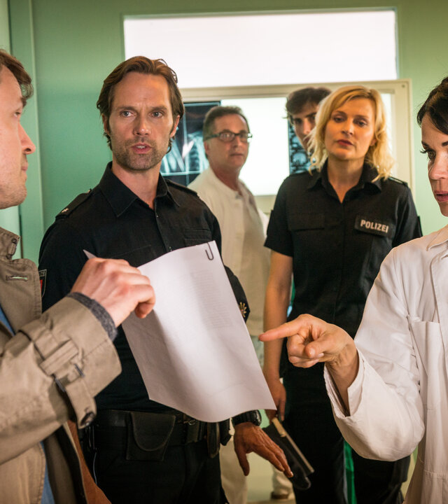 "Notruf Hafenkante: Kampf um Lucie": Torben Manstein (Daniel Aichinger), Dr. Jonas (Gerit Kling), der Polizeibeamte Mattes Seeler (Matthias Schloo) und seine Kollegin Melanie Hansen (Sanna Englund) befinden sich in einem Behandlungsraum des Elbkrankenhauses. Torben Manstein zeigt den Anwesenden ein Schriftstück.