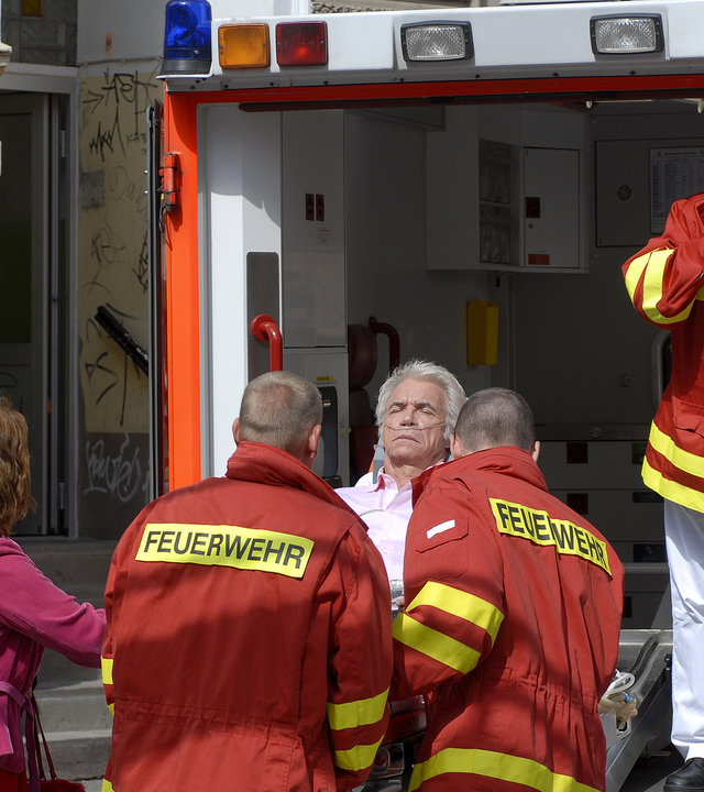 "Notruf Hafenkante - Luckys letzter Coup": Lucky (Wolf Roth) wird in den Krankenwagen verladen. Neben ihm steht seine Frau Manuela (Edda Leesch). Notarzt Dr. Haase (Fabian Harloff) steht im Krankenwagen und telefoniert.