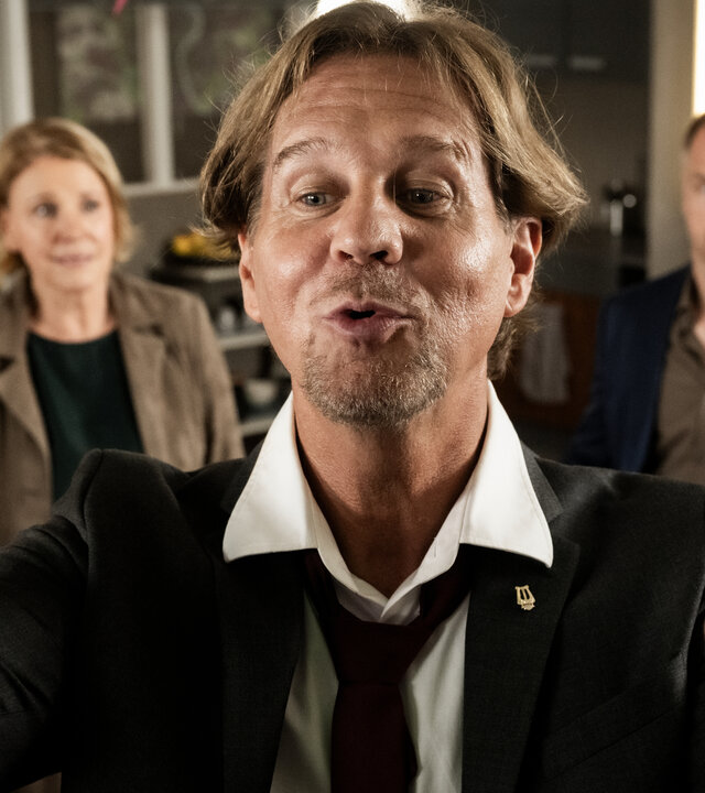 "Marie Brand und die verfolgte Braut": Marie Brand (Mariele Millowitsch) und Jürgen Simmel (Hinnerk Schönemann) stehen im Revier und schauen perplex zum rechten Bildrand. In der Mitte steht Dr. Engler (Thomas Heinze) mit gespitzten Lippen und dirigiert.