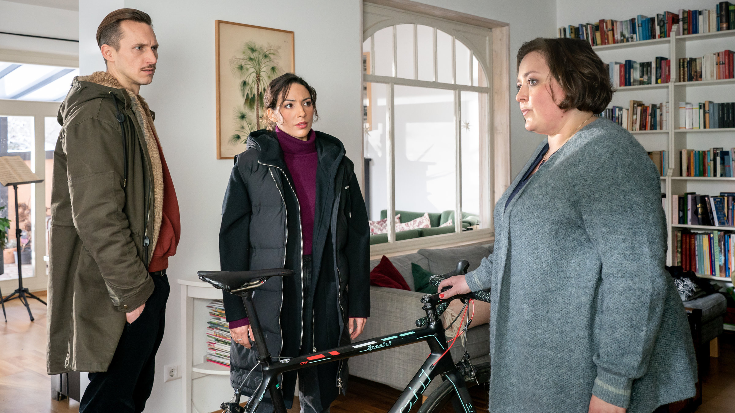 "SOKO Leipzig - Große Erwartungen": Moritz Brenner (Johannes Hendrik Langer) und Kim Nowak (Amy Mußul) stehen mit Selina Böhmer (Tina Pfurr) in ihrem Wohnzimmer um Marcs Fahrrad herum und unterhalten sich.