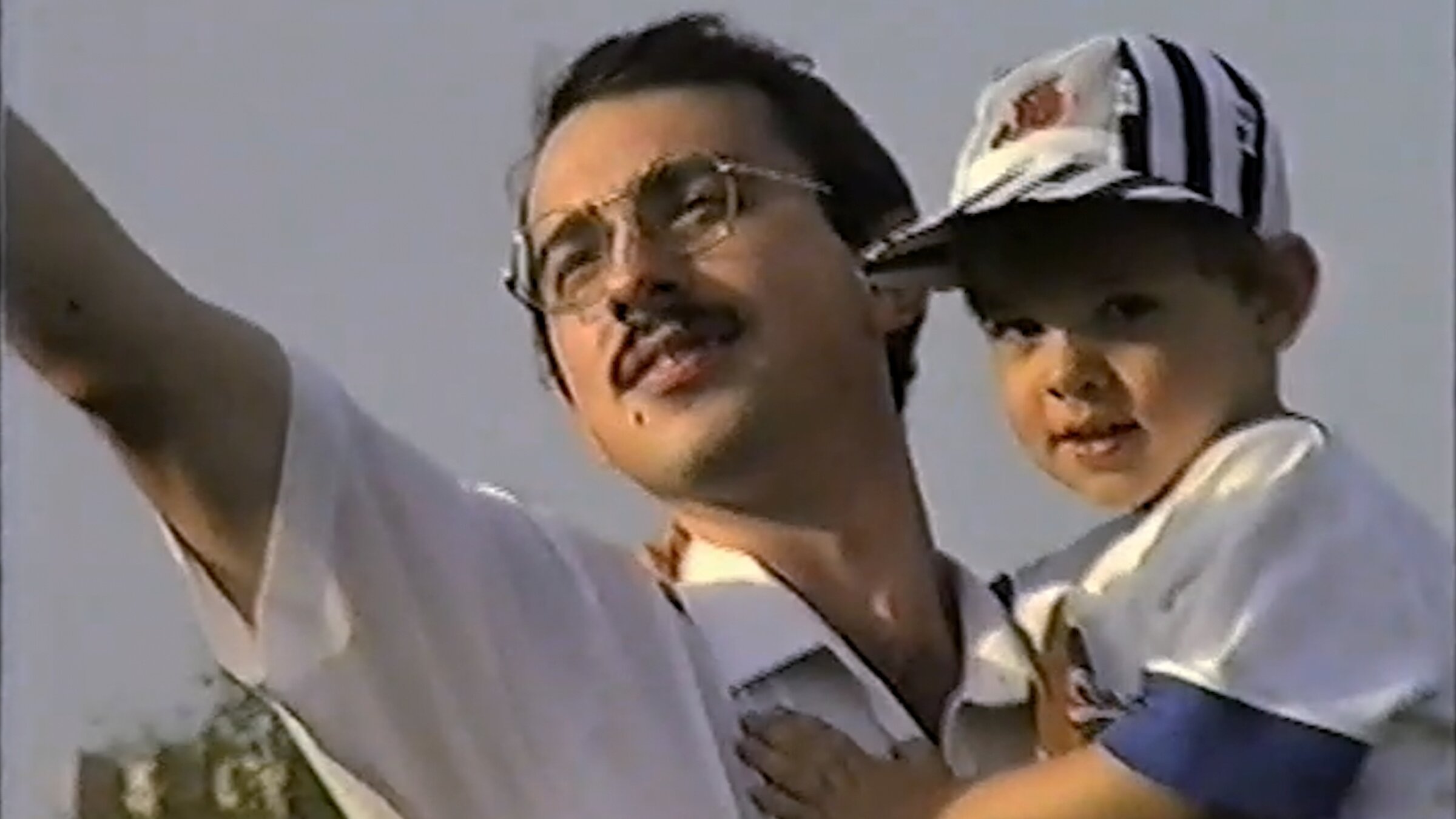 "Monument": Mann mit Kind auf Arm streckt einen Arm nach oben.