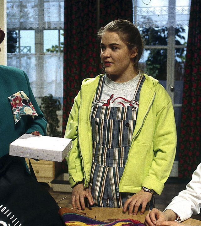 "Sprechstunde bei Dr. Frankenstein - Das unheimliche Erbe": Charly (Silke Matthias) sitzt in der Praxis am Tisch, Franzi (Floriane Eichhorn) und Frau Mompel (Ursula Staack) stehen daneben. Frau Mompel hält zwei Packungen in den Händen und spricht zu den beiden.