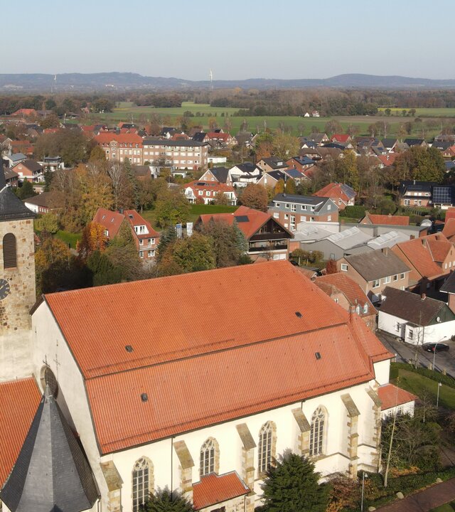 "Katholischer Gottesdienst - Ich freue mich auf dich!": Luftaufnahme der Pfarrkirche St. Johannis in Glandorf mit umliegenden Häusern