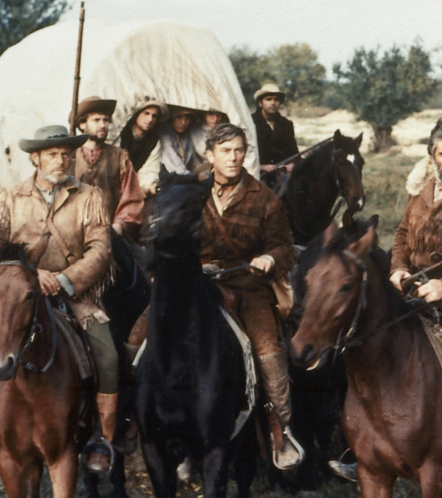 Abiram Bush (Mircea Pascu, l.), Nat Bumppo (Hellmut Lange, 2.v.l.), Miles Forman (Helmuth Schneider, 2.v.r.) und Chingachgook (Pierre Massimi, r.) beraten über den Weg des Siedlertrecks.