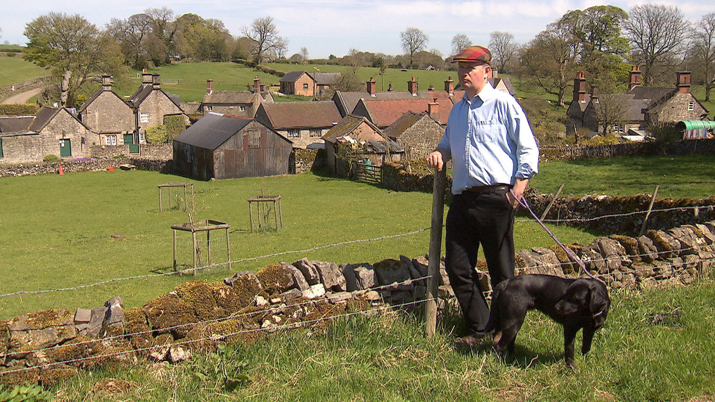 "England - Adel verpflichtet": Sir Richard Fitzherbert von Tissington Hall steht mit seinem Hund an einer  Steinmauer und schaut auf sein Dorf.