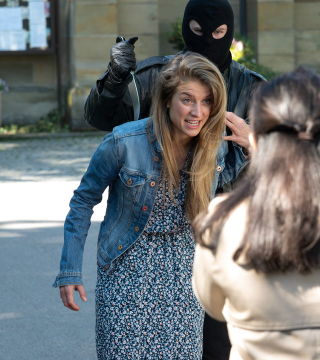 "SOKO Stuttgart – Tödliches Stuttgart": Die Stadtführerin Katja Schräter (Corinne Steudler) gibt eine ihrer Führungen. Ein vermummter Mitarbeiter, der als Verbrecher verkleidet ist, tut so, als ramme er ihr ein Messer in den Rücken. Die Touristen beobachten das Spektakel.