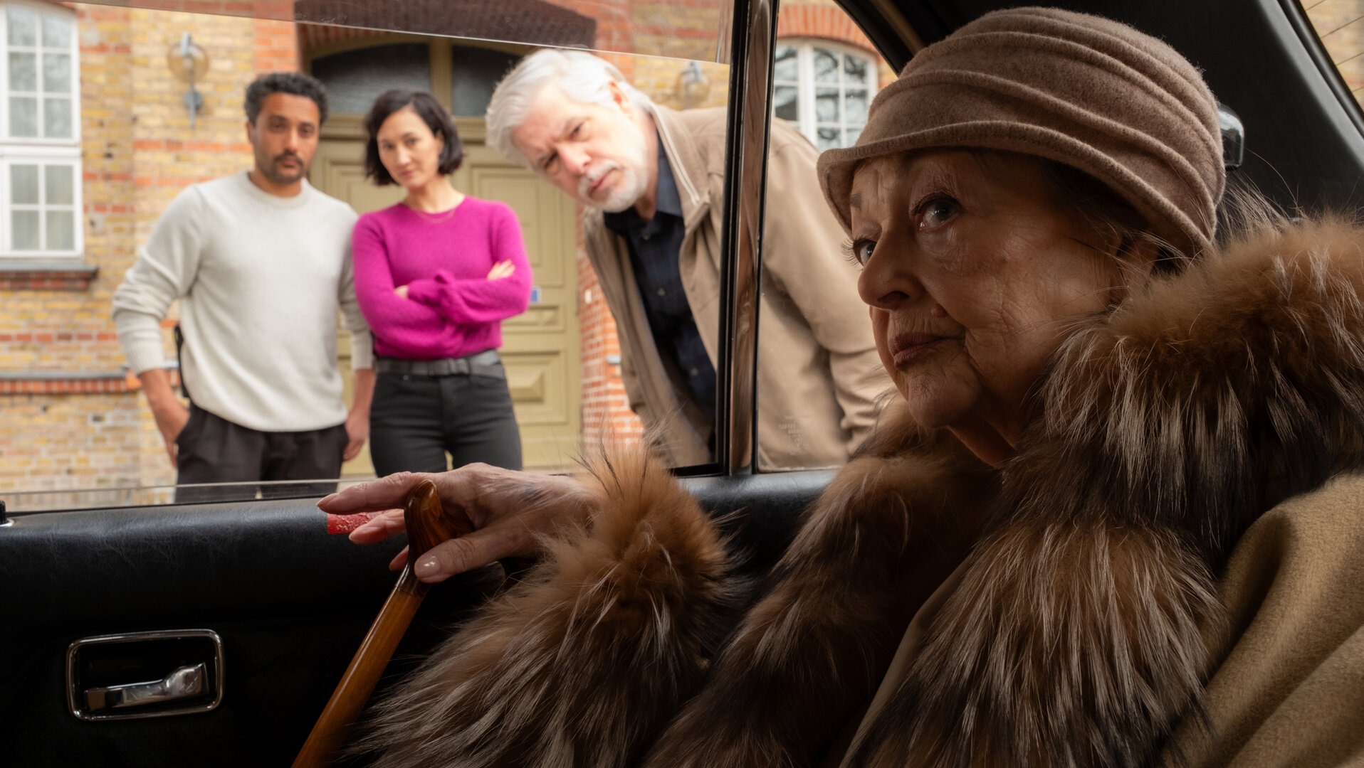 "SOKO Potsdam - Noch einmal Venedig": Gabriele Spickendorff (Barbara Schöne) sitzt im Auto, in einen Mantel mit breitem Pelzkragen gehüllt. Mit festem Blick schaut sie nach draußen. Durch das offene Fenster beugen sich die KommissarInnen Pauline Hobrecht (Agnes Decker) und David Grünbaum (Omar El-Saeidi) sowie ihr Fahrer Andreas Neumann (Peter René Lüdicke) zu ihr. Alle drei sehen sie ernst an.