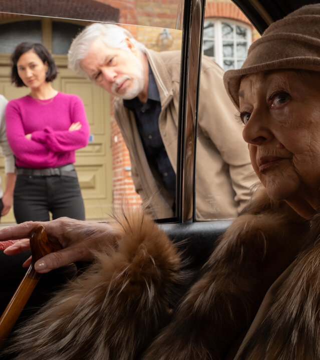 "SOKO Potsdam - Noch einmal Venedig": Gabriele Spickendorff (Barbara Schöne) sitzt im Auto, in einen Mantel mit breitem Pelzkragen gehüllt. Mit festem Blick schaut sie nach draußen. Durch das offene Fenster beugen sich die KommissarInnen Pauline Hobrecht (Agnes Decker) und David Grünbaum (Omar El-Saeidi) sowie ihr Fahrer Andreas Neumann (Peter René Lüdicke) zu ihr. Alle drei sehen sie ernst an.