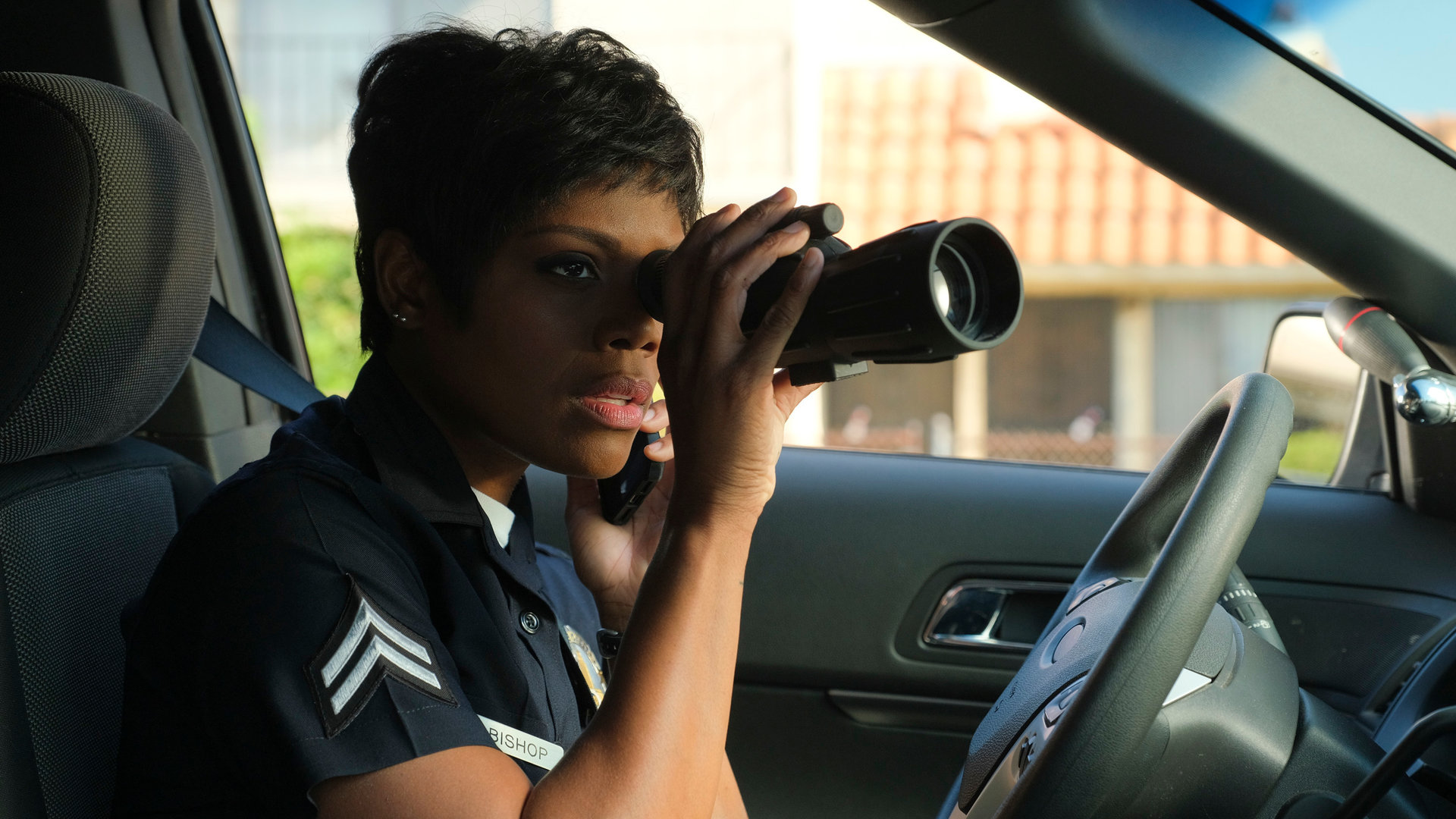 "The Rookie - Heimatfront": Talia Bishop (Afton Williamson) sitzt in einem Auto und schaut mit einem Fernrohr aus dem Fenster.