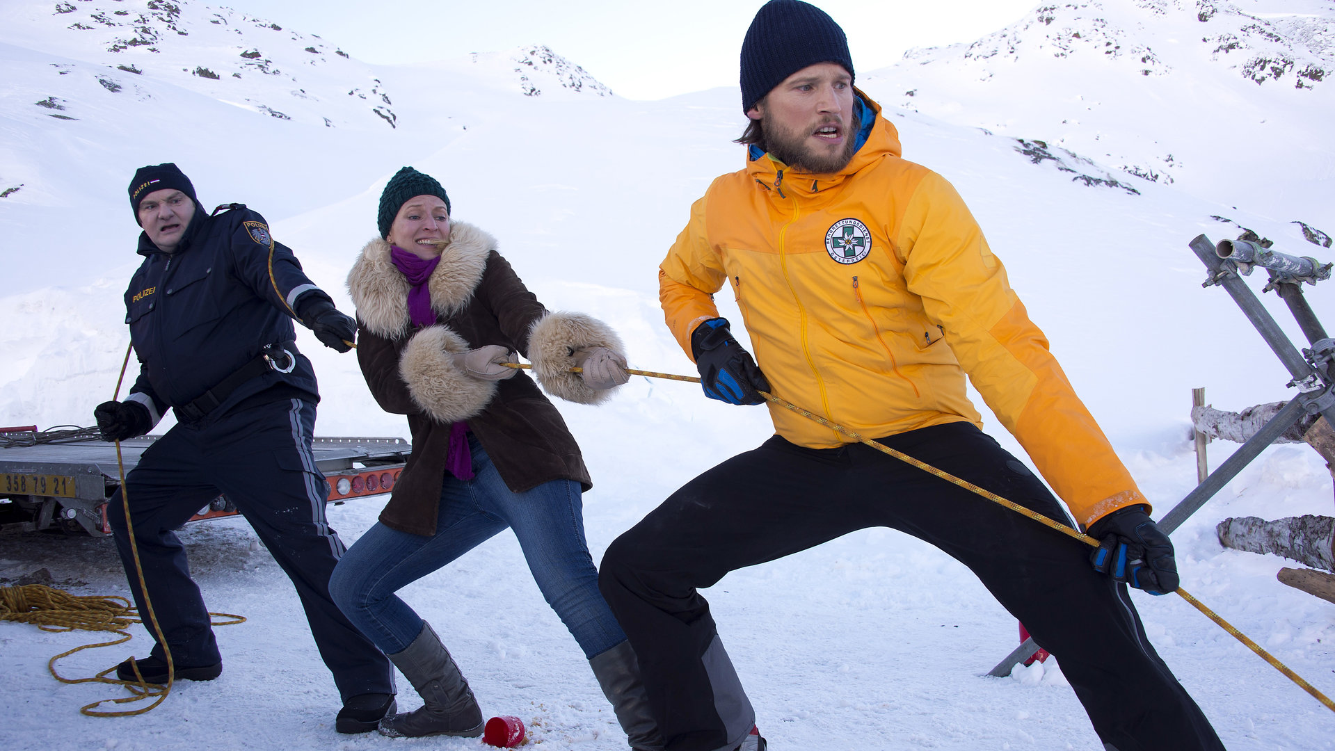 "Die Bergretter - Losgetreten (2)": Polizist Gert (Martin Leutgeb), Emilie (Stefanie von Poser) und Markus (Sebastian Ströbel) stehen an einem verschneiten Abhang und ziehen an einem Seil.