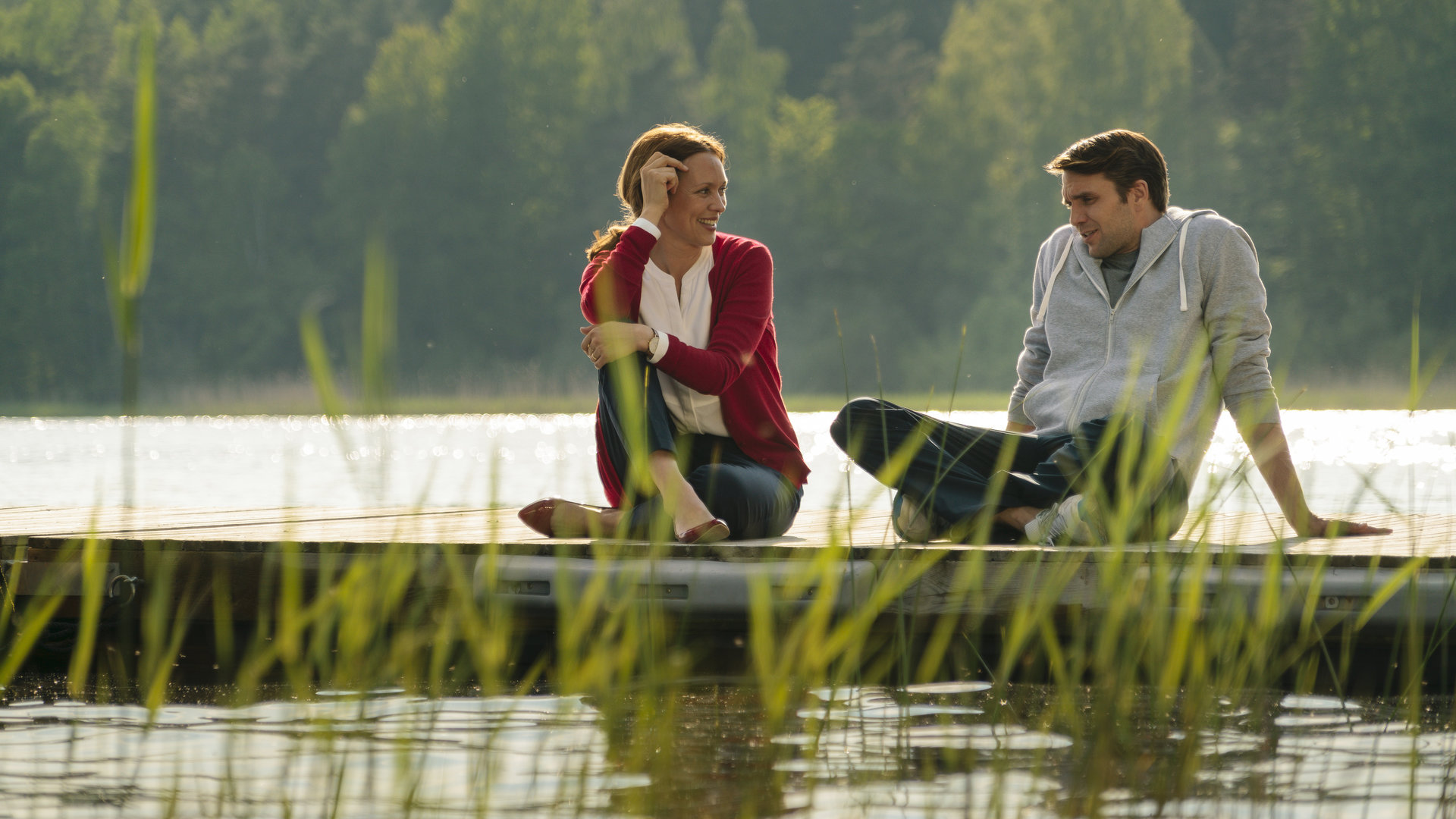 "Inga Lindström: Willkommen im Leben": Luisa Hanson (Nike Fuhrmann) und Ben (Pierre Kiwitt) sitzen am Steg und unterhalten sich lächelnd.