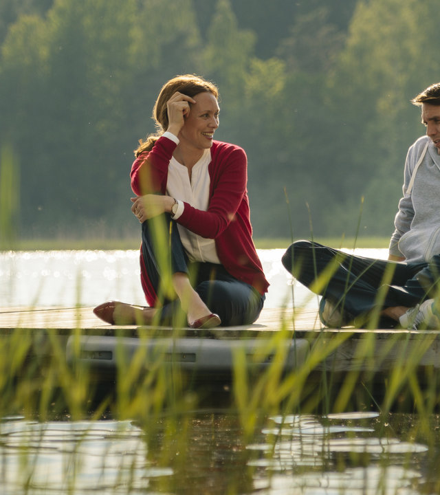 "Inga Lindström: Willkommen im Leben": Luisa Hanson (Nike Fuhrmann) und Ben (Pierre Kiwitt) sitzen am Steg und unterhalten sich lächelnd.