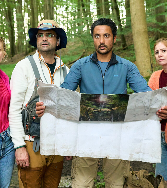 "Dr. Nice - Die Natur der Liebe": Naturpädagoge Deniz Birol (Omar El-Saeidi) hält eine Landkarte vor sich und erklärt den verwundert schauenden Teilnehmenden an seiner Exkursion in die Natur, was für Aufgaben sie zu lösen haben. Nice (Patrick Kalupa) sieht nicht begeistert aus, Charlie (Josefine Preuß) steht neben ihm und schaut skeptisch, während Dr. Schmidtke (Maximilian Grill) und seine Frau Jana (Tereza Rizos) aussehen, als ob sie sich auf den Ausflug freuen.