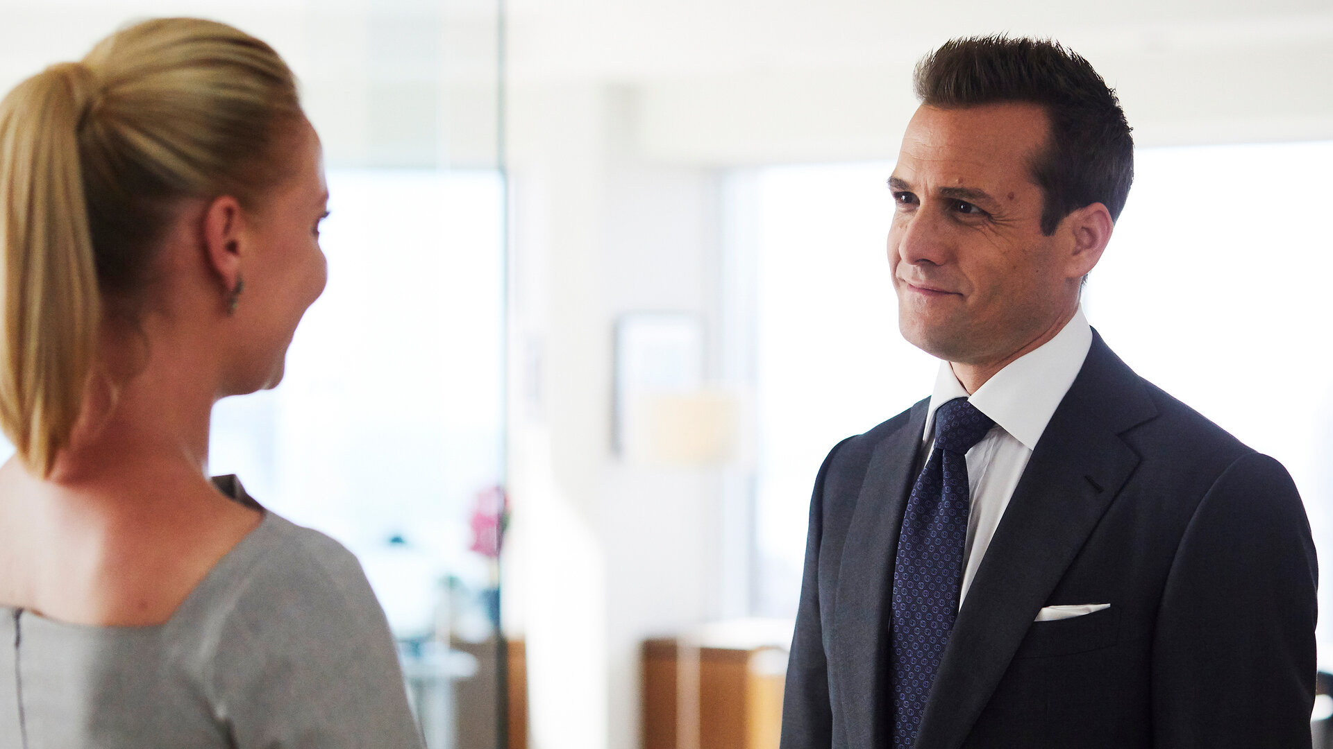"Suits - Coral Gables": Harvey (Gabriel Macht) steht mit einem eleganten, dunklen Anzug bekleidet Samantha (Katherine Heigl) gegenüber, die im Profil zu erkennen ist. Er lächelt sie offen an.