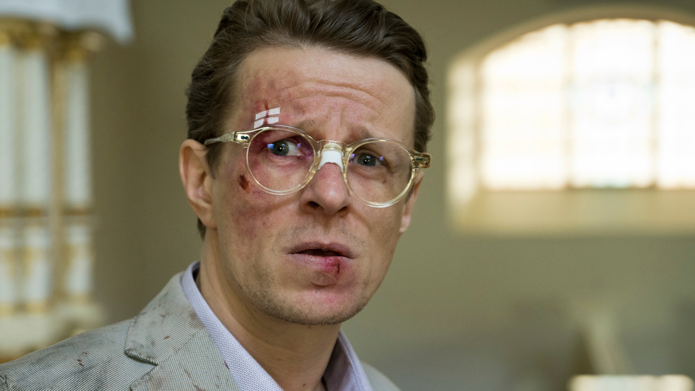 Sløborn: Starautor Nikolai Wagner (Alexander Scheer) sieht mit lädiertem Gesicht besorgt in die Kamera. An seiner Kleidung ist getrocknetes Blut.