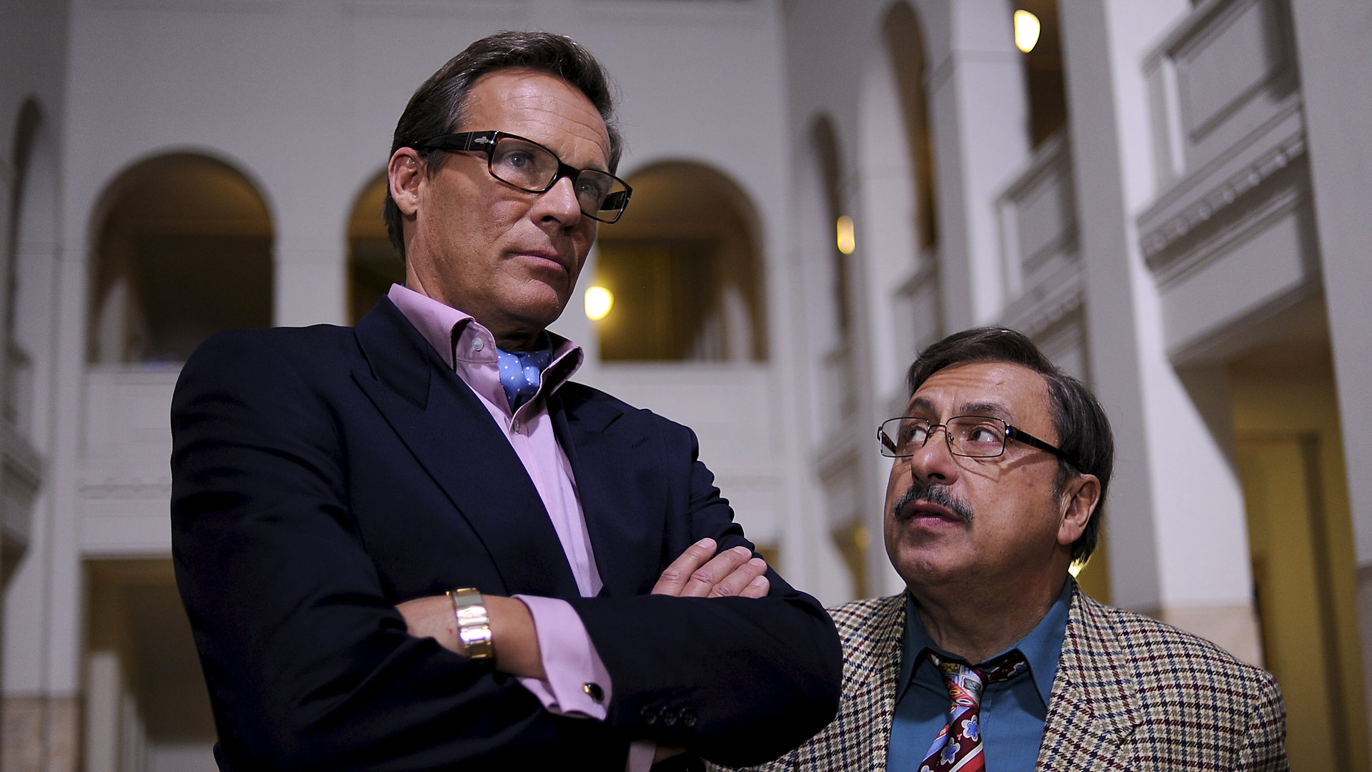 "Stankowskis Millionen": Werner Stankowski (Wolfgang Stumph) steht mit Rene Vonderecken (Christian Tramitz) in der Empfangshalle der Treuhand und schaut skeptisch zu ihm auf. Vonderecken steht mit verschränken Armen neben ihm und schaut in die Ferne.