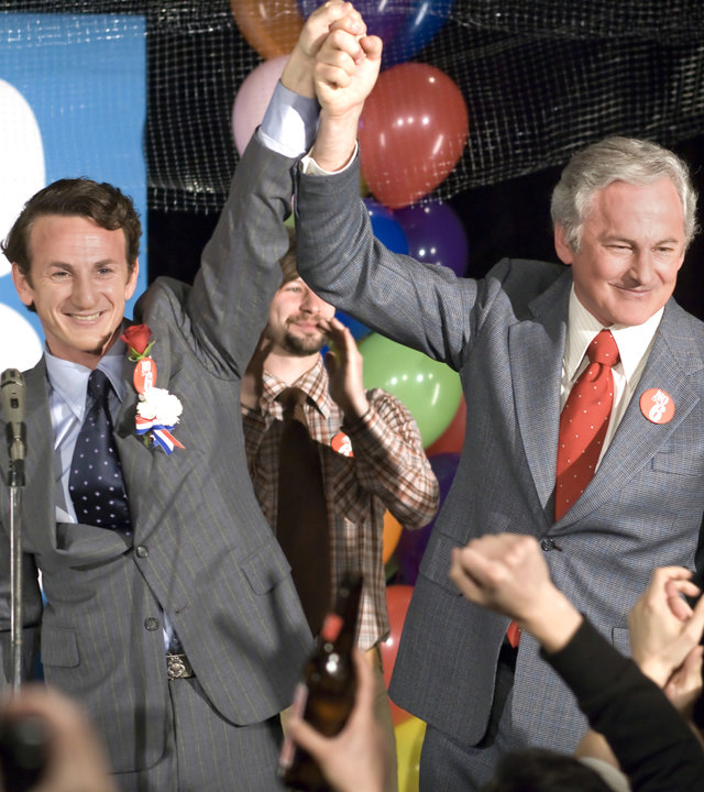 "Milk": Harvey Milk (Sean Penn) und Bürgermeister Moscone (Victor Garber) stehen gemeinsam auf einer Bühne vor klatschendem Publikum. Sie heben ihre Hände in die Luft und lächeln.