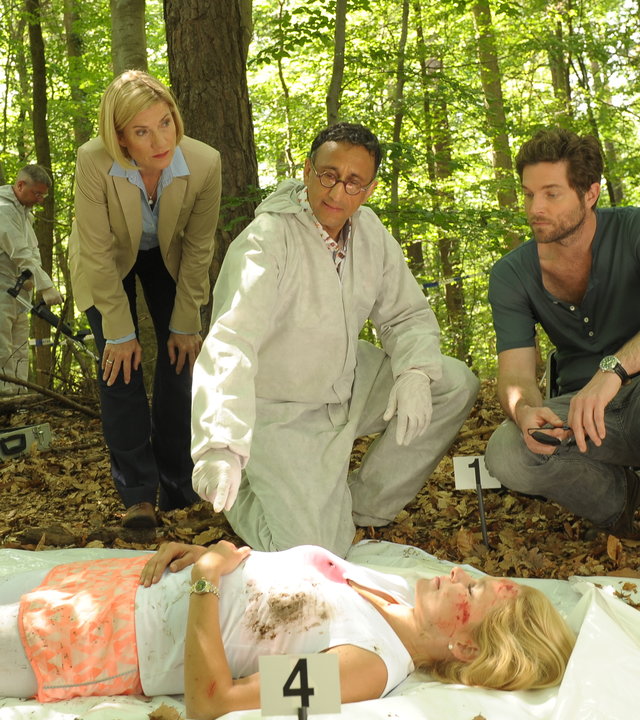 "SOKO Stuttgart - In guten Händen": Martina Seiffert (Astrid M. Fünderich) und Jo Stoll (Peter Ketnath) stehen im Wald beim Opfer Sabine Dombrowski (Komparsin). KTU-Leiter Jan Arnaud (Mike Zaka Sommerfeldt) deutet auf die Hände der Toten, während im Hintergrund ein Spurensicherer (Komparse) den Boden mit einem Metalldetektor absucht.