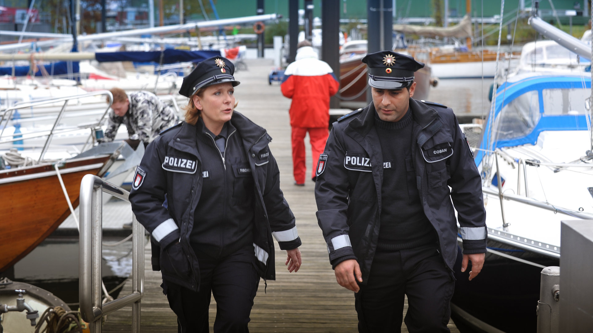 "Notruf Hafenkante - Eltern - nein, danke!": Claudia (Janette Rauch) und Tarik (Serhat Cokgezen) laufen am Yachthafen entlang und sehen sich um.