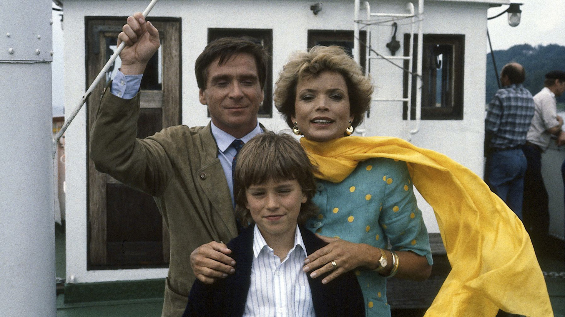 "Zwei Münchner in Hamburg - Abschied von der Isar": Julia Heiniger (Uschi Glas) und ihr Sohn Max (Florian Stubenvoll) stehen zusammen mit Dr. Sagerer (Elmar Wepper) auf einem Ausflugsboot. Julias gelber Schal weht im Wind.