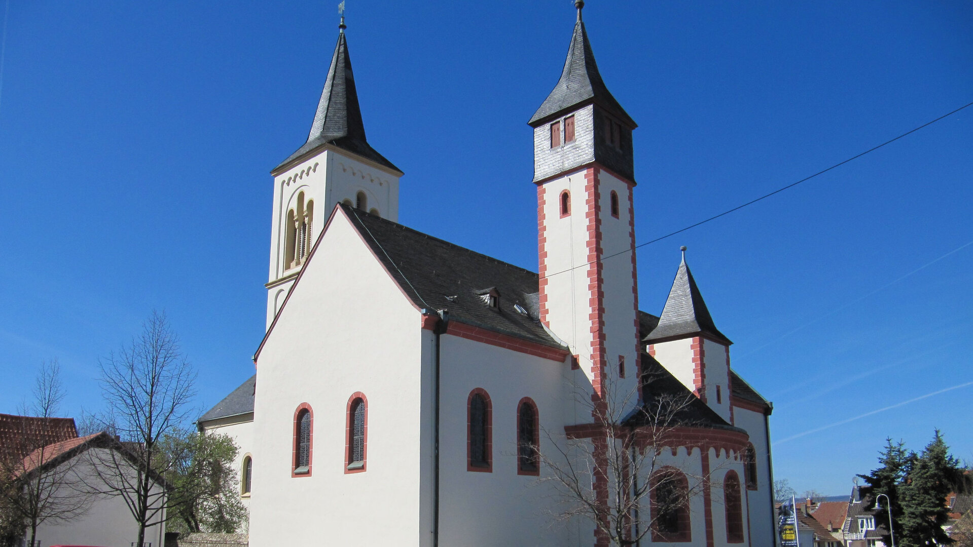 "Evangelischer Gottesdienst – Kopf hoch": Vor strahlend blauem Himmel hebt sich das Weiß der Ingelheimer Saalkirche mit ihren drei filigranen Türmen ab.