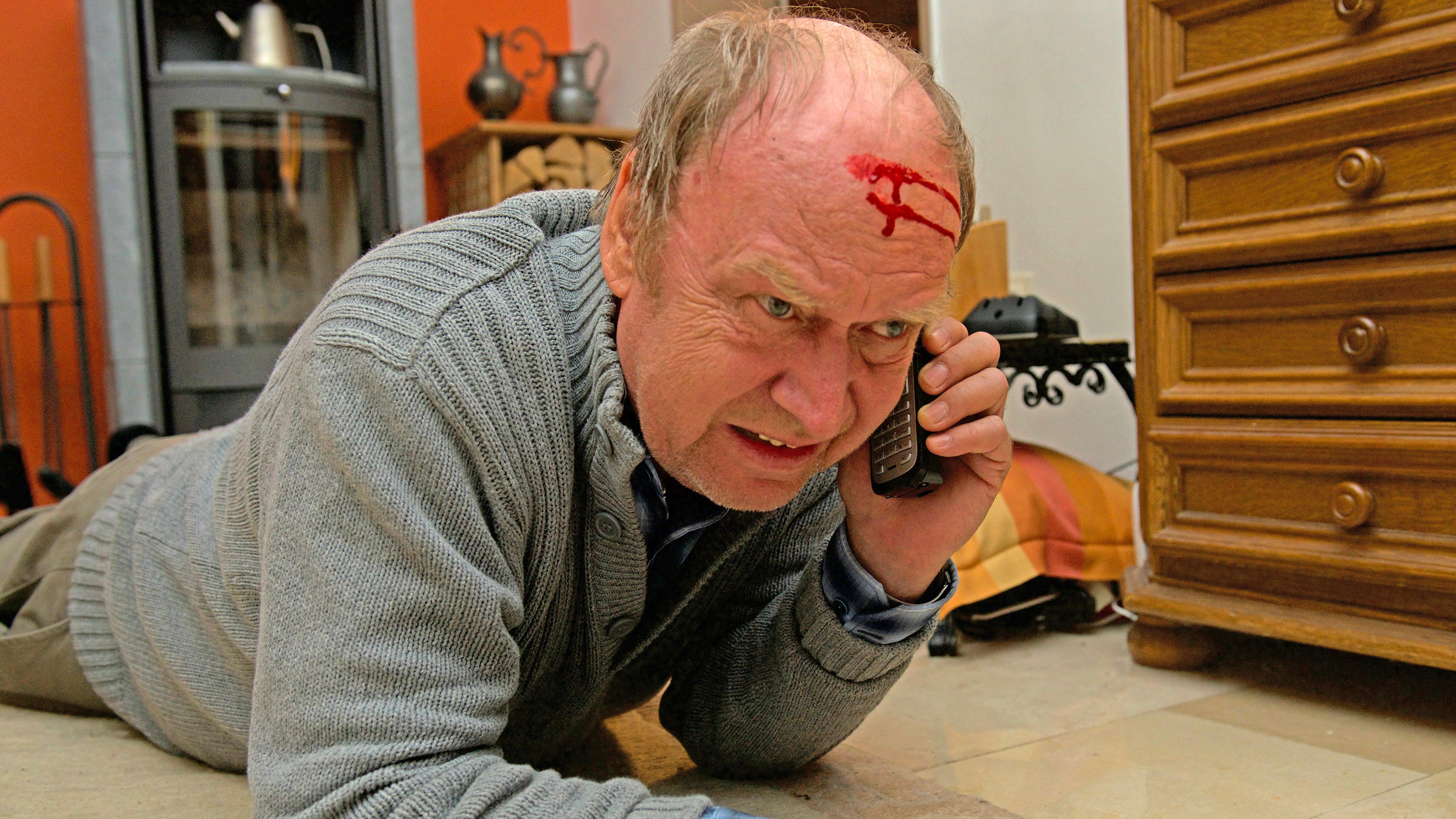 "Aktenzeichen XY... gelöst": Ein älterer Mann liegt auf dem Boden, er blutet an der Stirn. Sichtbar mit letzter Kraft hält er ein Handy am Ohr und telefoniert.