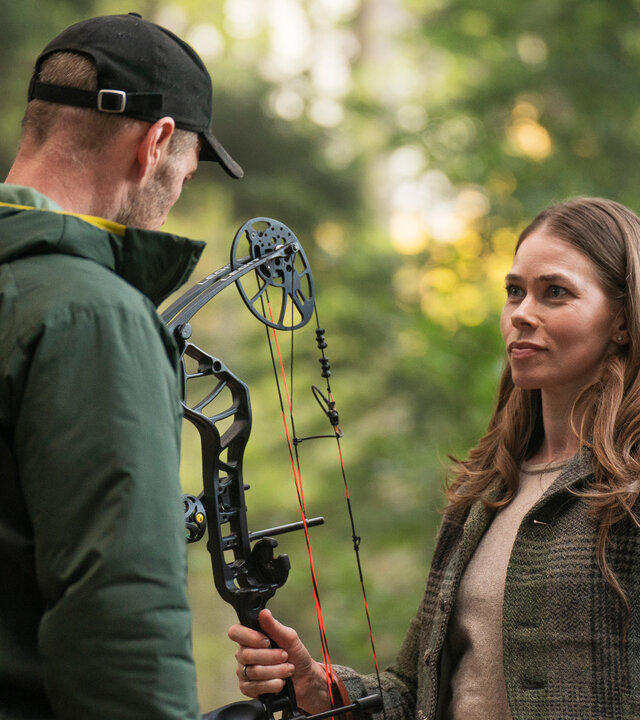 "Oxen - Ein neues Spiel": Kajsa (Birgitte Hjort Sørensen) und Niels (Jacob Lohmann) stehen sich im Wald gegenüber. Sie hält einen Sportbogen in der rechten Hand.