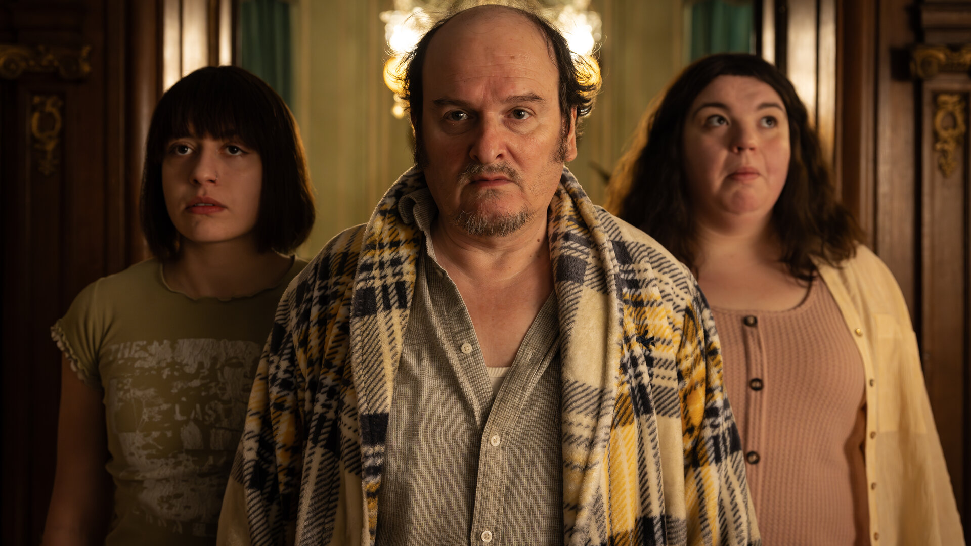 "How to Kill Your Sister - Folge 3": Anna (Emma Rotsaert), Rémi (Roland Vouilloz) und Kat (Marjan De Schutter) stehen nebeneinander in einem Raum. Im Hintergrund hängt ein Kronleuchter. Die beiden Frauen wirken überrascht.