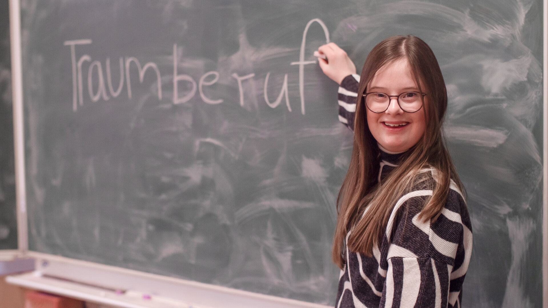 "einfach Mensch - Charlotte Henning: Durch Inklusion zum Traumberuf": Charlotte Henning schreibt das Wort "Traumberuf" an eine Schultafel.