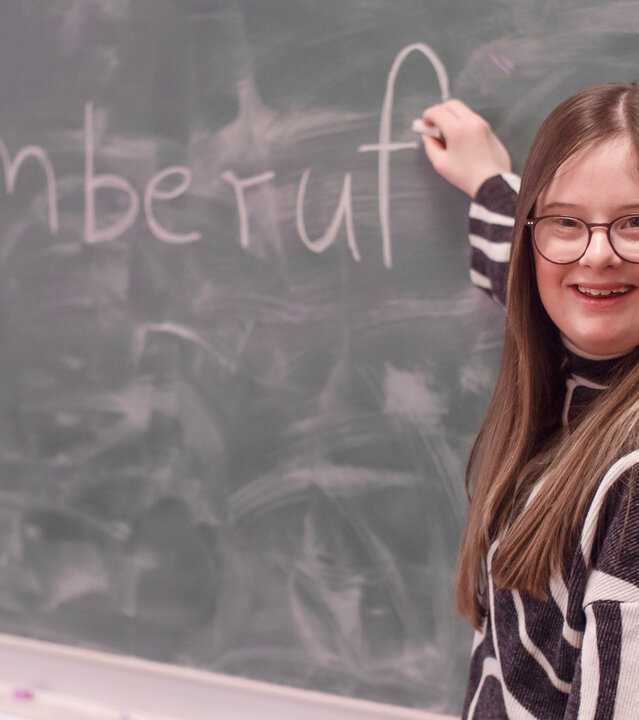 "einfach Mensch - Charlotte Henning: Durch Inklusion zum Traumberuf": Charlotte Henning schreibt das Wort "Traumberuf" an eine Schultafel.