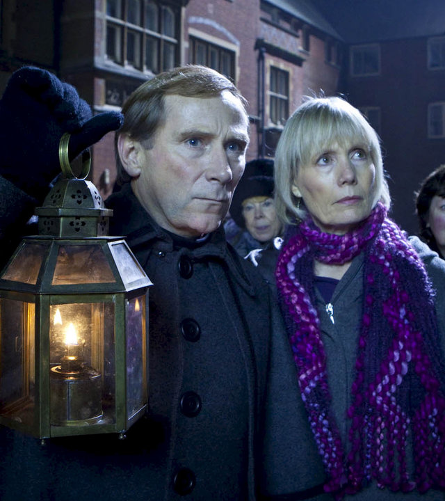 "Inspector Barnaby - Geisterwanderung": Jeff Bowmaker (Danny Webb) und Joyce Barnaby (Jane Wymark) stehen im Dunkeln vor einem Haus. Hinter ihnen stehen weitere Personen.