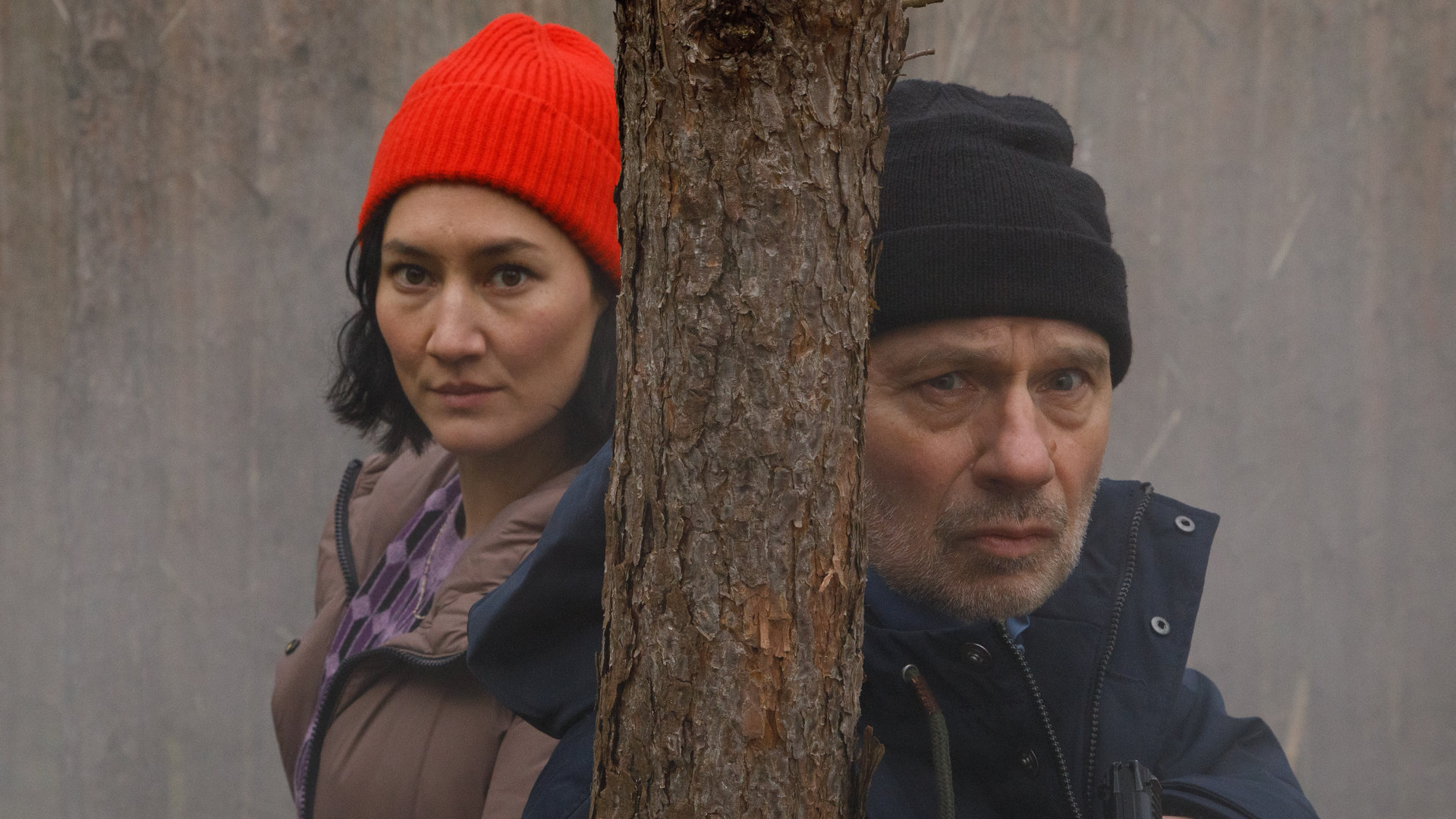 "SOKO Potsdam - Brieselanger Licht": Pauline Hobrecht (Agnes Decker) und Bernhard Henschel (Michael Lott) stehen konzentriert im Brieselanger Wald hinter einem schmalen Baumstamm im Nebel.