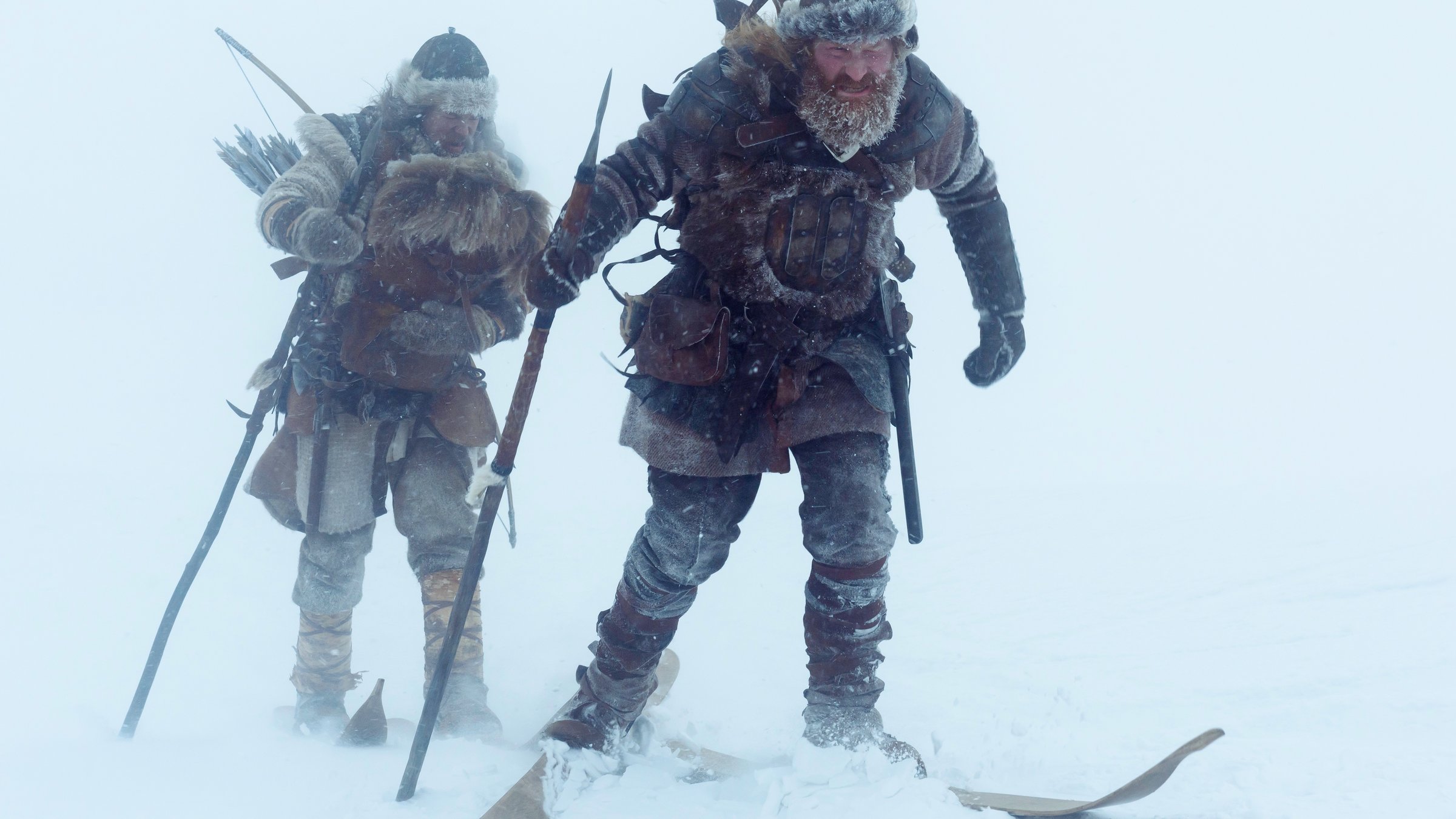 "The Last King - Schlacht der Könige": Skjervald (Jakob Oftebro) und Torstein (Kristofer Hivju) marschieren auf ihren Skiern durch eine Schneelandschaft. Torstein läuft voran und im Hintergrund ist Skjervald zu sehen, der ein Baby auf dem Arm hat.