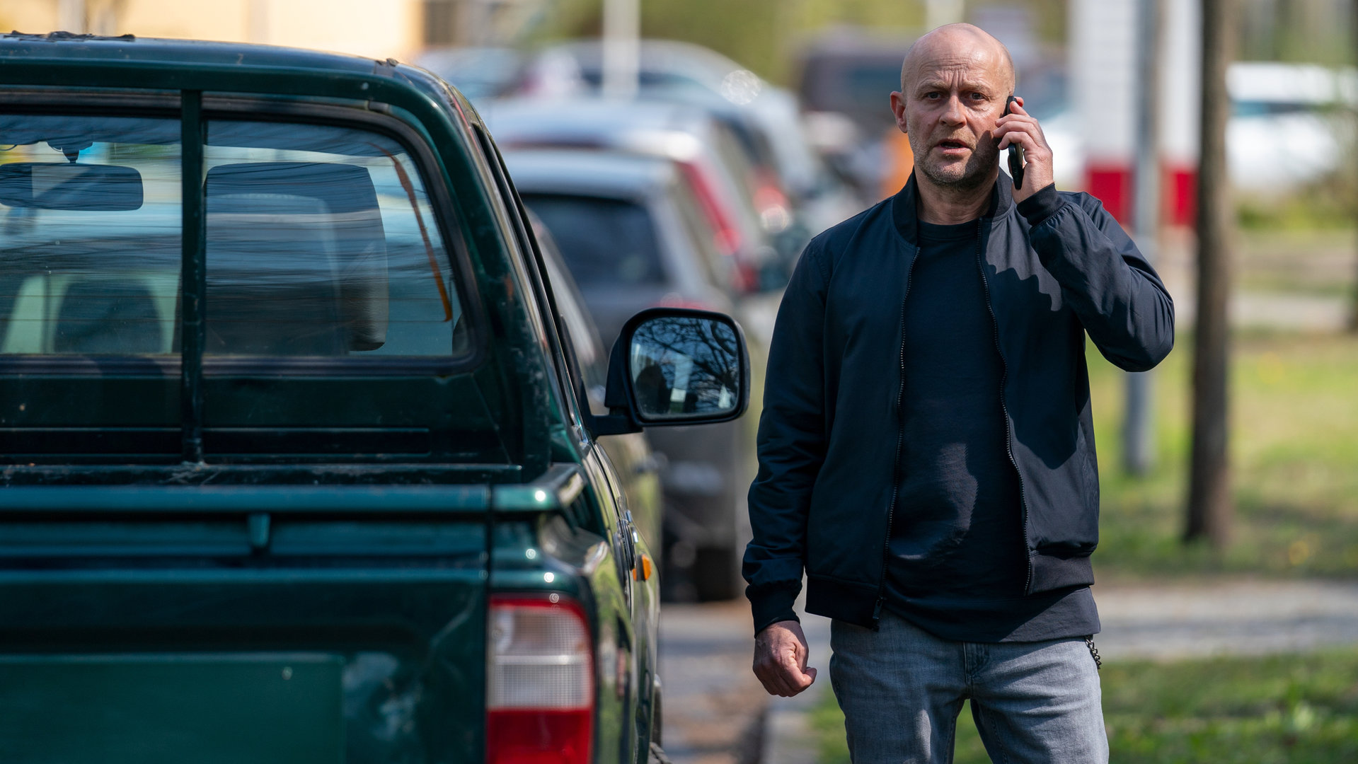 "Jenseits der Spree - Du bist mein": Robert (Jürgen Vogel) steht neben einem parkenden Auto und telefoniert mit seinem Mobiltelefon.