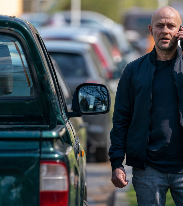 "Jenseits der Spree - Du bist mein": Robert (Jürgen Vogel) steht neben einem parkenden Auto und telefoniert mit seinem Mobiltelefon.