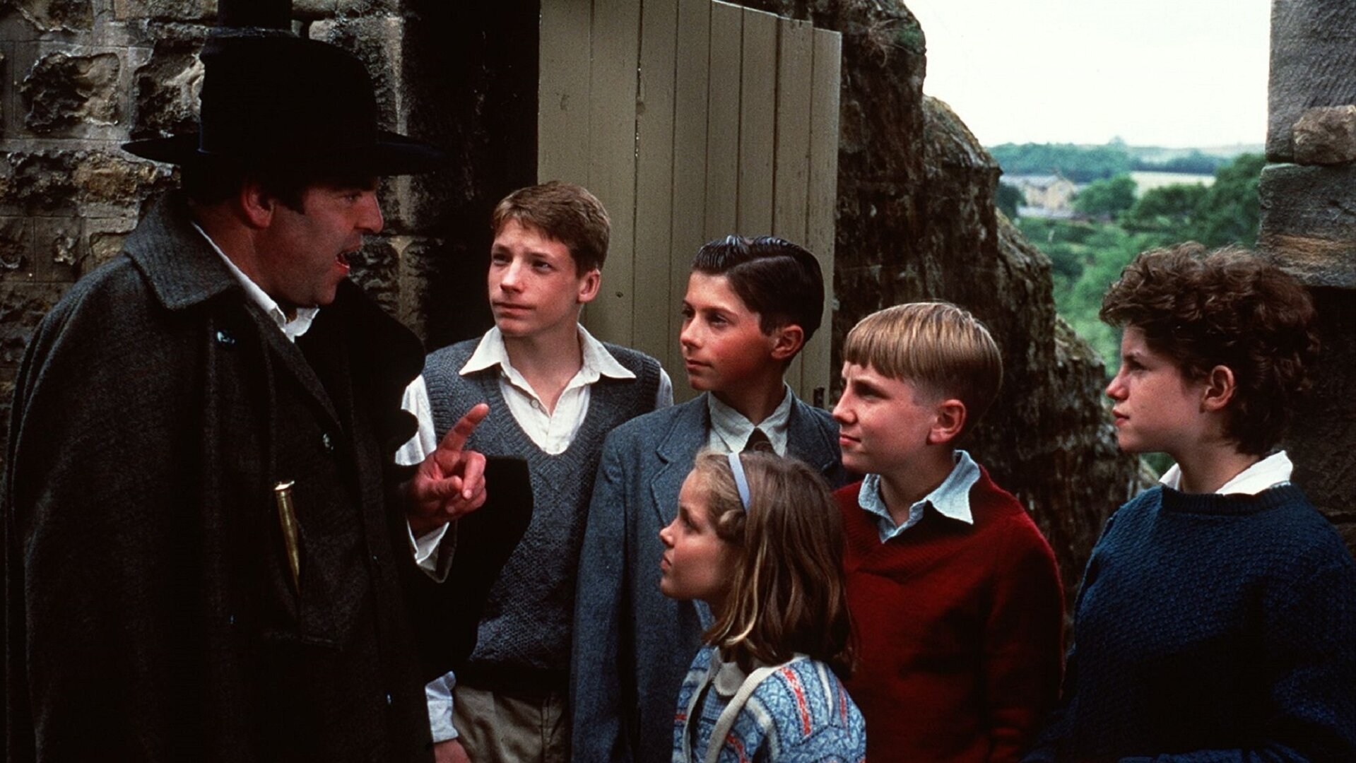 "Fünf Freunde auf Schmugglerjagd (1)": Die Kinder Julian (Marco Williamson), Pete (Ian Aherne), Dick (Paul Child), George (Jemima Rooper) und Anne (Laura Petela) blicken aufmerksam zu Barling (Jeremy Sinden), der vor ihnen steht und mit erhobenem Zeigefinger etwas erklärt.